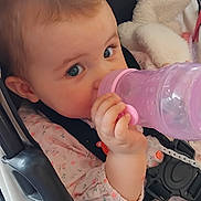 Lucie a rejoint le concours — aidez-le/la à gagner de superbes lots ! baby, blanket, blue_eyes, bottle, child, closeup, clothing, comfort, cute, drinking, face, hand, indoor, infant, person, pink, pink_bottle, seatbelt, soft_toys, stroller