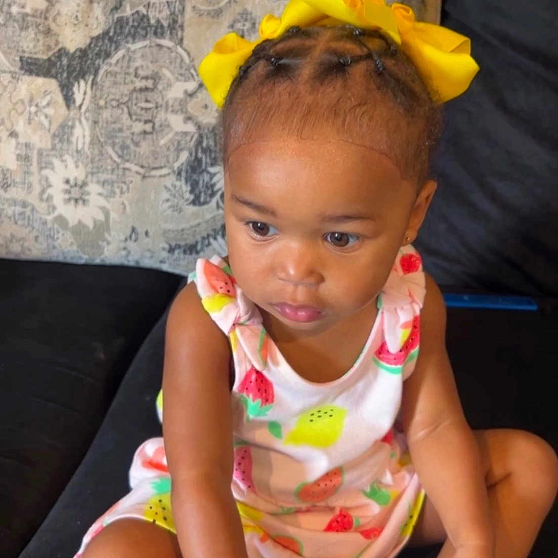Alayla joined the competition — help win amazing prizes! black_couch, braided_hair, child, couch, curious, cute, dress, expression, fashion, fruit_pattern, girl, home, indoor, person, portrait, sitting, socks, toddler, yellow_bow, young_child