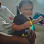Eddonia Smith joined the competition — help win amazing prizes! toddler, child, smiling, person, adult, indoor, living_room, carpet, toy, clothing, black_shirt, hand, curly_hair, baby, happy, seated, family, playful, casual, home