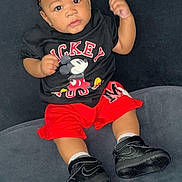 Bryston joined the competition — help win amazing prizes! baby, black_background, black_shoes, casual_clothing, child, couch, curious_expression, cute, fashion, indoor, mickey_mouse, person, photography, portrait, red_shorts, seated, shirt, sneakers, toddler, young_child