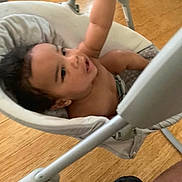 Kalil joined the competition — help win amazing prizes! baby, child, swing, indoor, toy, plush_toy, wooden_floor, person, reaching, smiling, happy, seat, cushion, footwear, black_shoe, playtime, infant, arm, expression, home
