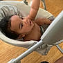 baby, child, swing, indoor, toy, plush_toy, wooden_floor, person, reaching, smiling, happy, seat, cushion, footwear, black_shoe, playtime, infant, arm, expression, home