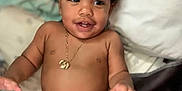 Kalil is registered to the contest to win money with this photo: toddler, child, baby, smiling, curly_hair, necklace, bare_chest, blanket, pillow, bed, indoor, happy, skin, hand, face, young_child, infant, cute, person, relaxed
