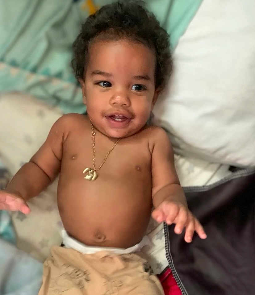 Kalil is registered to the contest to win money with this photo: toddler, child, baby, smiling, curly_hair, necklace, bare_chest, blanket, pillow, bed, indoor, happy, skin, hand, face, young_child, infant, cute, person, relaxed