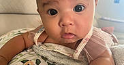 Adriana joined the competition — help win amazing prizes! baby, infant, child, portrait, close_up, face, wide_eyes, looking_at_camera, sitting, blanket, floral_pattern, baby_clothing, pink, home, indoors, couch, soft_lighting, adorable, curious, photograph