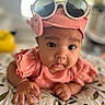 baby, infant, child, portrait, sunglasses, pink_outfit, hat, fashion, adorable, staring, indoor, bed, blanket, floral_pattern, leaf_pattern, close_up, face, hands, soft_lighting, photography