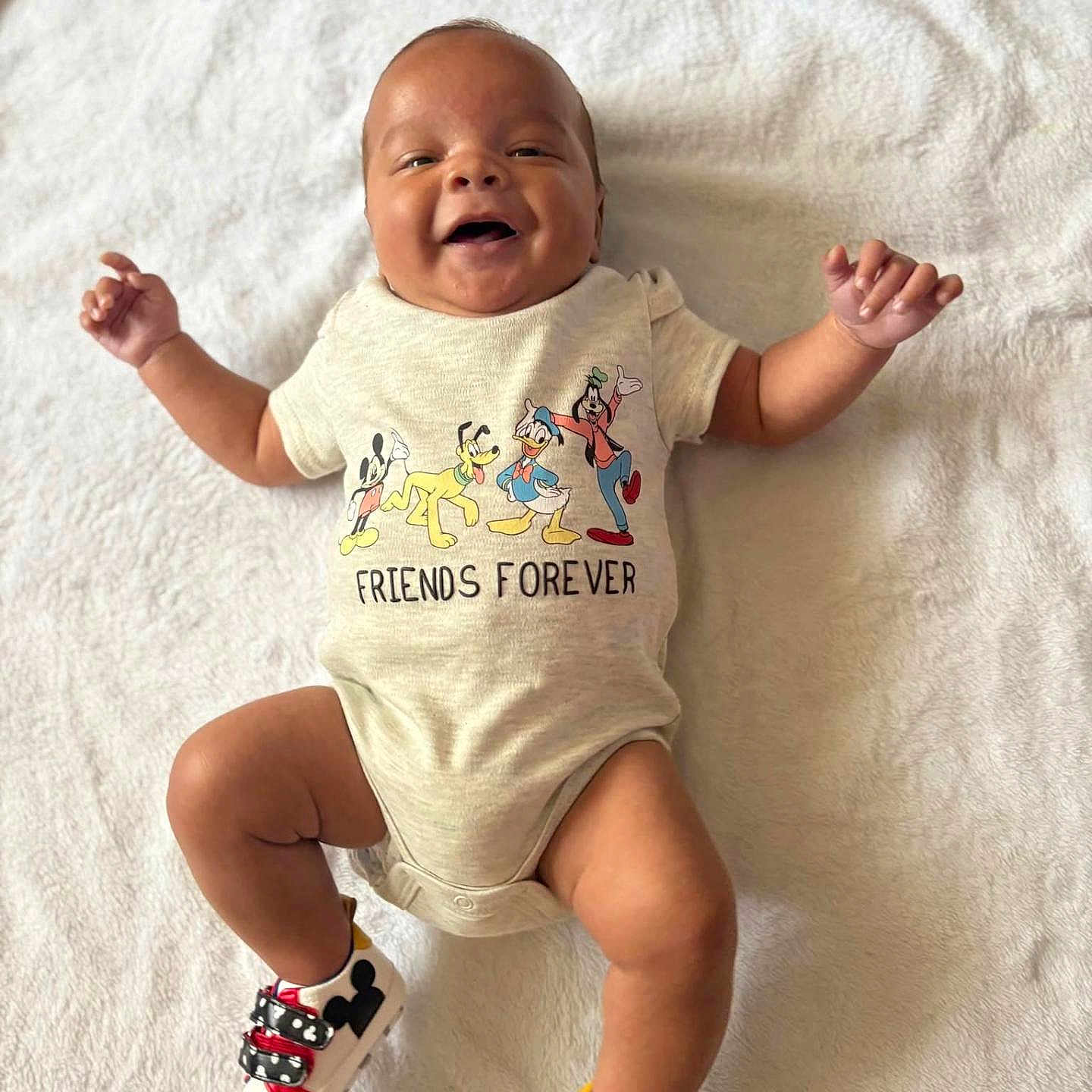 Mi'Zeir is registered to the contest to win money with this photo: baby, baby_shoes, child, clothing, cute, disney, donald_duck, feet, friends_forever, goofy, happy, infant, lying_down, mickey_mouse, onesie, pluto, portrait, shoes, smiling, white_blanket