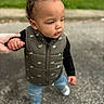 Mi'Zeir is registered to the contest to win money with this photo: blurred_background, casual_clothing, child, curious, curly_hair, daylight, green_vest, holding_hand, jeans, nike, outdoor, pavement, person, side_view, sneakers, standing, support, toddler, walking, young_child
