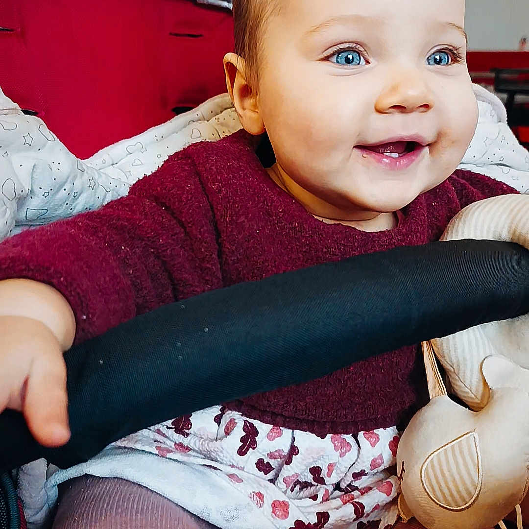 Lys a rejoint le concours — aidez-le/la à gagner de superbes lots ! baby, blue_eyes, child, clothing, cozy, cute, fabric, face, hand, happy, indoor, infant, person, plush_toy, portrait, seat, sitting, smiling, stroller, toddler