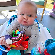 Braxton joined the competition — help win amazing prizes! baby, child, toy, high_chair, colorful, soft_toy, indoor, pout, curious, plastic_toys, blue, turquoise, seat, clothing, long_sleeve, cute, face, hands, infant, person