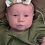 baby, infant, face, headband, bow, green_clothing, ribbed_fabric, closeup, portrait, chubby_cheeks, blue_eyes, curious_expression, skin, person, child, cute, young, indoors, texture, brown_background