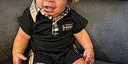 Jose is registered to the contest to win money with this photo: baby, child, smiling, hat, plaid, black_clothing, couch, indoor, cute, portrait, happy, person, sitting, feet, toes, infant, young_child, fashion, comfortable, cozy