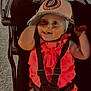 baby, child, stroller, cap, pink_clothing, smile, happy, face, infant, seatbelt, outdoor, person, cute, headwear, cheerful, young, sitting, baby_girl, closeup, portrait