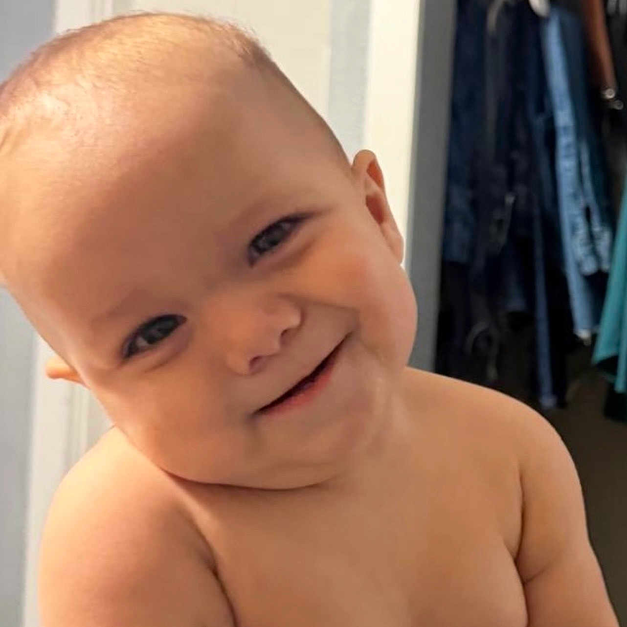 Nicolas is registered to the contest to win money with this photo: baby, infant, child, smiling, portrait, close_up, face, head, bare_shoulders, skin, eyes, nose, mouth, indoor, home, closet, clothing, doorway, warm_lighting, happy