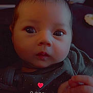 Story is registered to the contest to win money with this photo: baby, clothing, cute, dark_background, emoji, expression, eyes, face, hand, head, indoors, infant, looking, love, person, portrait, sitting, skin, time, young_child