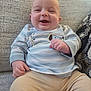 Braxton joined the competition — help win amazing prizes! baby, smiling, child, infant, couch, striped_shirt, dog_design, beige_pants, happy, sitting, indoors, cozy, cute, person, face, hand, clothing, texture, fabric, relaxed