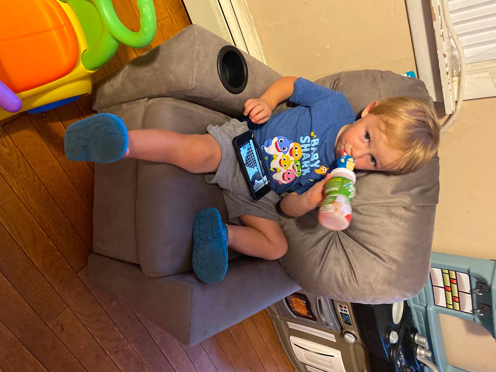 Lincoln is registered to the contest to win money with this photo: baby, baby_products, baby_toddler_clothing, baby_toys, child, comfort, flooring, fun, leg, leisure, person, play, recreation, room, sitting, sneakers, t_shirt, thigh, toddler, toy