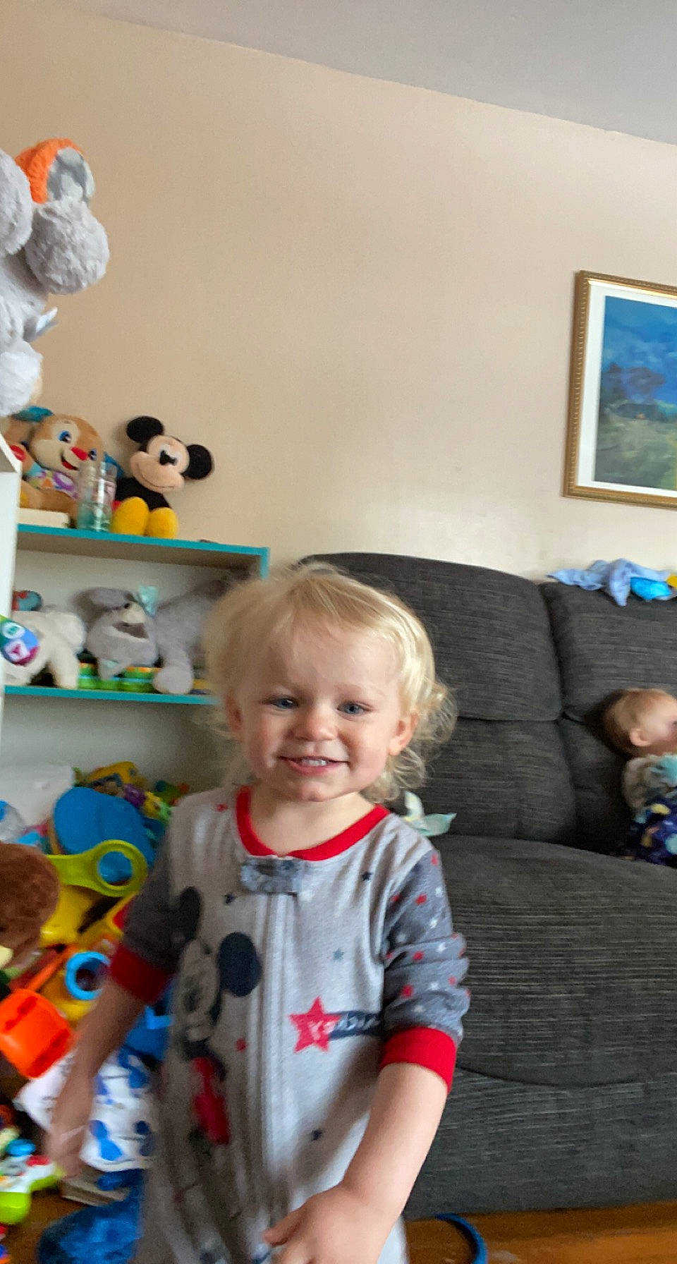 Maverick is registered to the contest to win money with this photo: baby, baby_toddler_clothing, baby_toys, blue, child, couch, doll, fun, happy, joy, living_room, person, picture_frame, play, room, shelf, shelving, sitting, smile, t_shirt