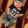 Kaiden joined the competition — help win amazing prizes! baby, infant, child, black_clothing, hat, striped_hat, pants, barefoot, armchair, red, gold, striped_fabric, cute, chubby_cheeks, portrait, seated, indoor, expression, young_child, comfortable