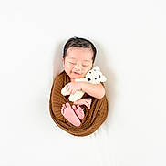 Akharvan joined the competition — help win amazing prizes! newborn, baby, sleeping, wrapped, brown_cloth, teddy_bear, crocheted_toy, soft_background, white, peaceful, smiling, cute, infant, portrait, tiny_feet, hands, cozy, serene, child, studio_photo