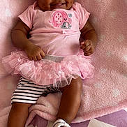 Saeyora is registered to the contest to win money with this photo: baby, smiling, pink, headband, tutu, blanket, cute, infant, dimples, clothing, footwear, striped_shorts, happy, lying_down, soft_texture, indoors, child, person, portrait, fashion
