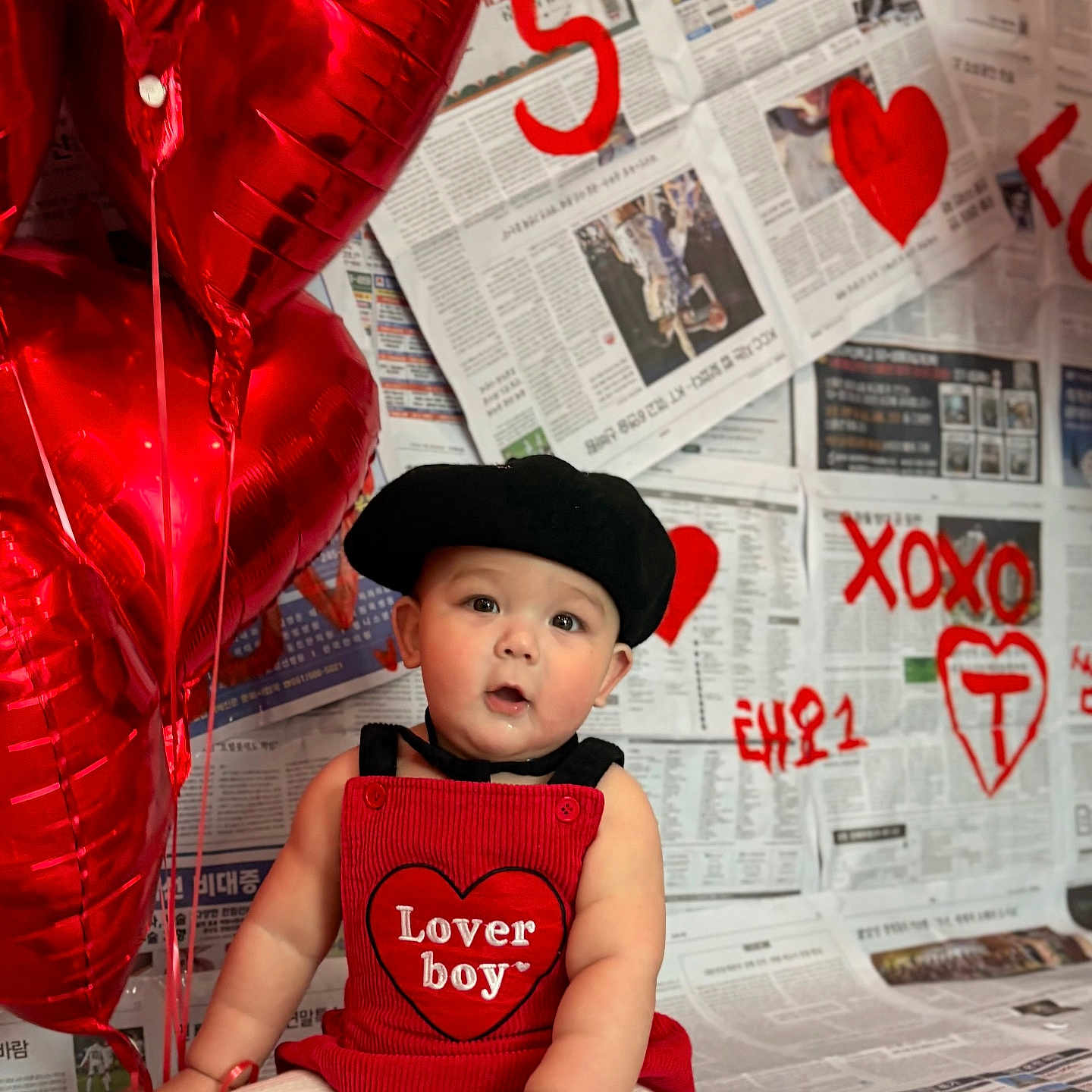 Taeo is registered to the contest to win money with this photo: baby, balloons, beret, child, clothing, cute, decor, expression, graffiti, heart, indoor, love, newspaper, person, photography, portrait, red, sitting, valentines_day, xoxo