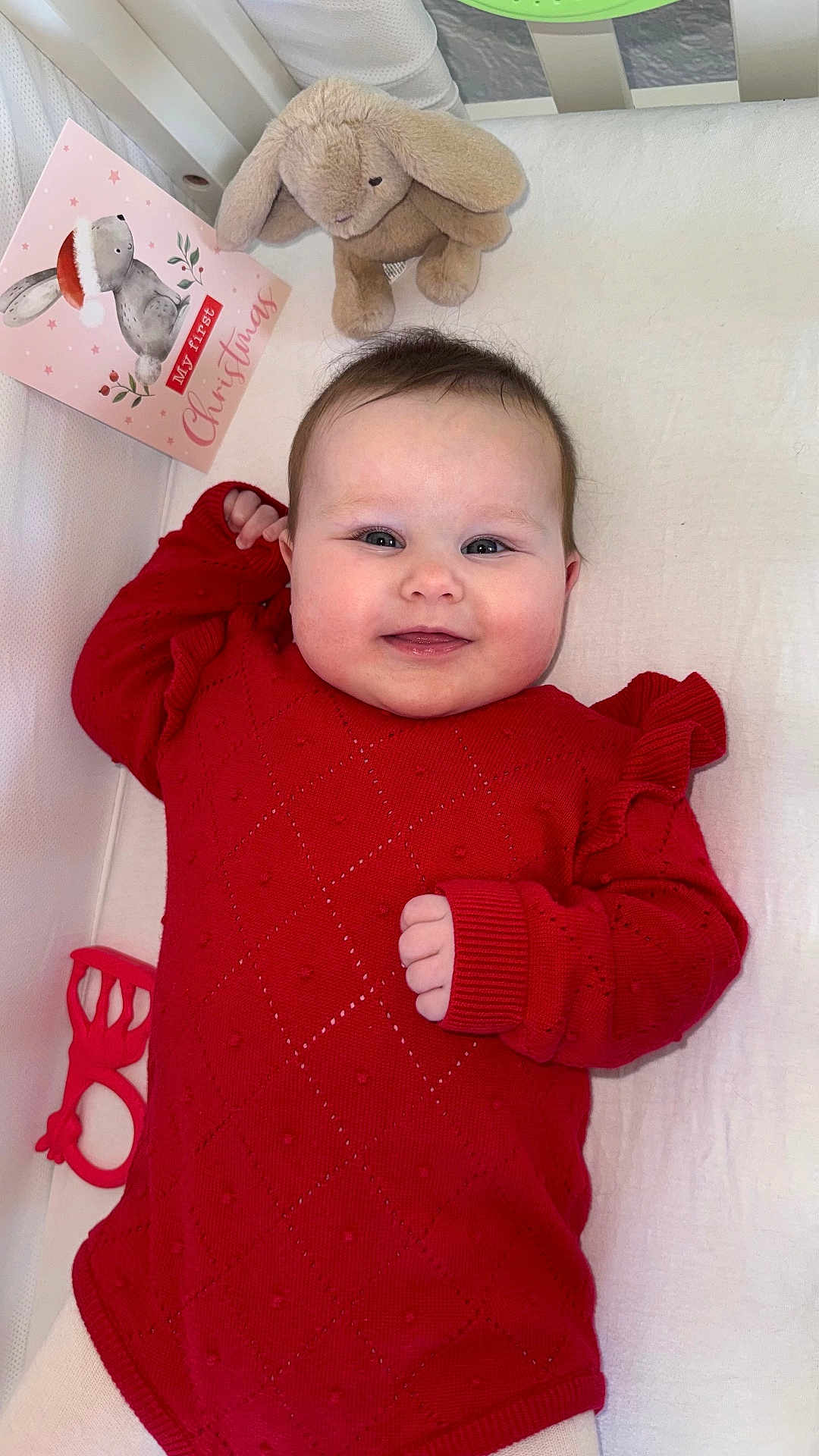 Luna is registered to the contest to win money with this photo: baby, infant, smiling, red_sweater, plush_toy, crib, christmas_card, holiday, cute, child, lying_down, happy, indoors, soft_toy, festive, cozy, portrait, celebration, toy, seasonal