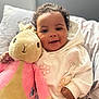 Myla joined the competition — help win amazing prizes! baby, child, plush_toy, bunny, smiling, hoodie, yellow_pants, bed, pillow, blanket, cute, soft_toy, happy, indoors, person, face, curly_hair, cozy, seated, comfort