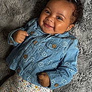 Myla joined the competition — help win amazing prizes! baby, smiling, denim_jacket, floral_pattern, pants, blanket, curly_hair, cute, happy, portrait, infant, clothing, child, face, hands, button, texture, cozy, lying_down, soft
