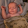 baby, sleeping, blanket, floral_pattern, arms_up, cozy, infant, bedding, peaceful, soft_lighting, child, newborn, portrait, indoors, cute, relaxed, skin, person, resting, comfort