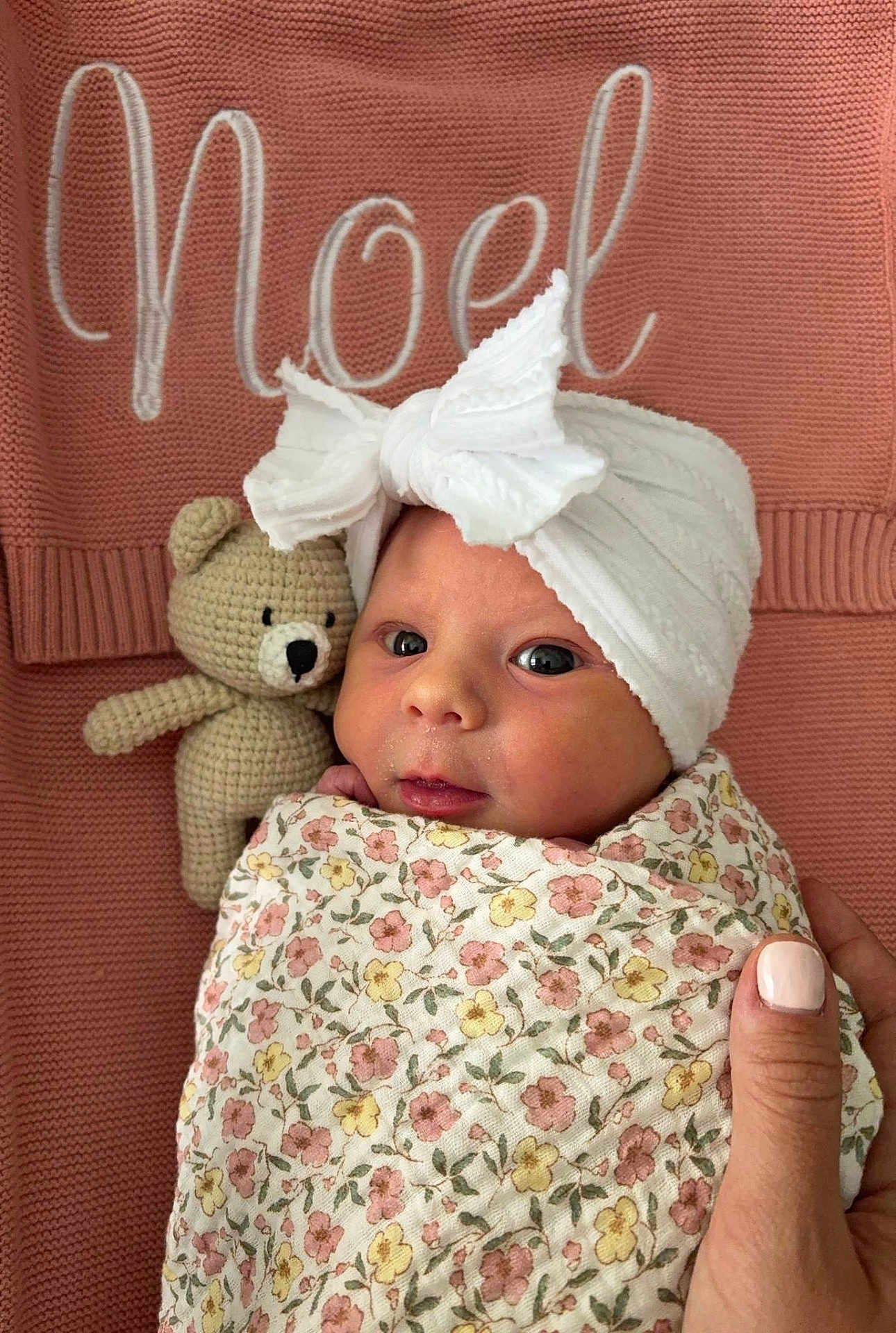 Noel joined the competition — help win amazing prizes! newborn, baby, infant, wrapped, blanket, floral_pattern, headwrap, bow, crocheted_toy, teddy_bear, pink_background, knitted, cozy, cute, portrait, hand, nail_polish, face, eyes, indoors