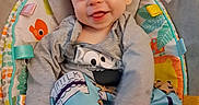 River joined the competition — help win amazing prizes! baby, infant, child, smiling, tongue_out, portrait, sitting, bouncer, baby_seat, blanket, clothing, gray_shirt, blue_socks, toys, colorful, indoor, home, happy, face, cozy