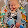 River joined the competition — help win amazing prizes! baby, infant, child, smiling, tongue_out, portrait, sitting, bouncer, baby_seat, blanket, clothing, gray_shirt, blue_socks, toys, colorful, indoor, home, happy, face, cozy