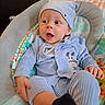 baby, child, infant, portrait, blue_hat, blue_clothing, mickey_mouse, cushioned_seat, baby_chair, sitting, wide_eyed, open_mouth, indoors, colorful, blanket, patterned_fabric, hands, legs, cozy, happy