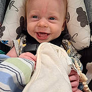 River is registered to the contest to win money with this photo: baby, infant, child, smiling, happy, portrait, car_seat, blanket, toy, pacifier, baby_toy, harness, seated, close_up, face, indoors, vehicle, patterned_fabric, cozy, photography