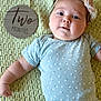 baby, infant, child, headband, flower, onesie, blanket, texture, sign, wood, milestone, portrait, cute, lying_down, skin, face, smile, small_person, happy, closeup