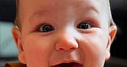 Larry joined the competition — help win amazing prizes! adorable, baby, blurred_background, brown_clothing, child, close_up, eyes, face, hair, happy, indoor, infant, open_mouth, photography, portrait, sitting, sleeveless_outfit, smiling, surprised, warm_lighting