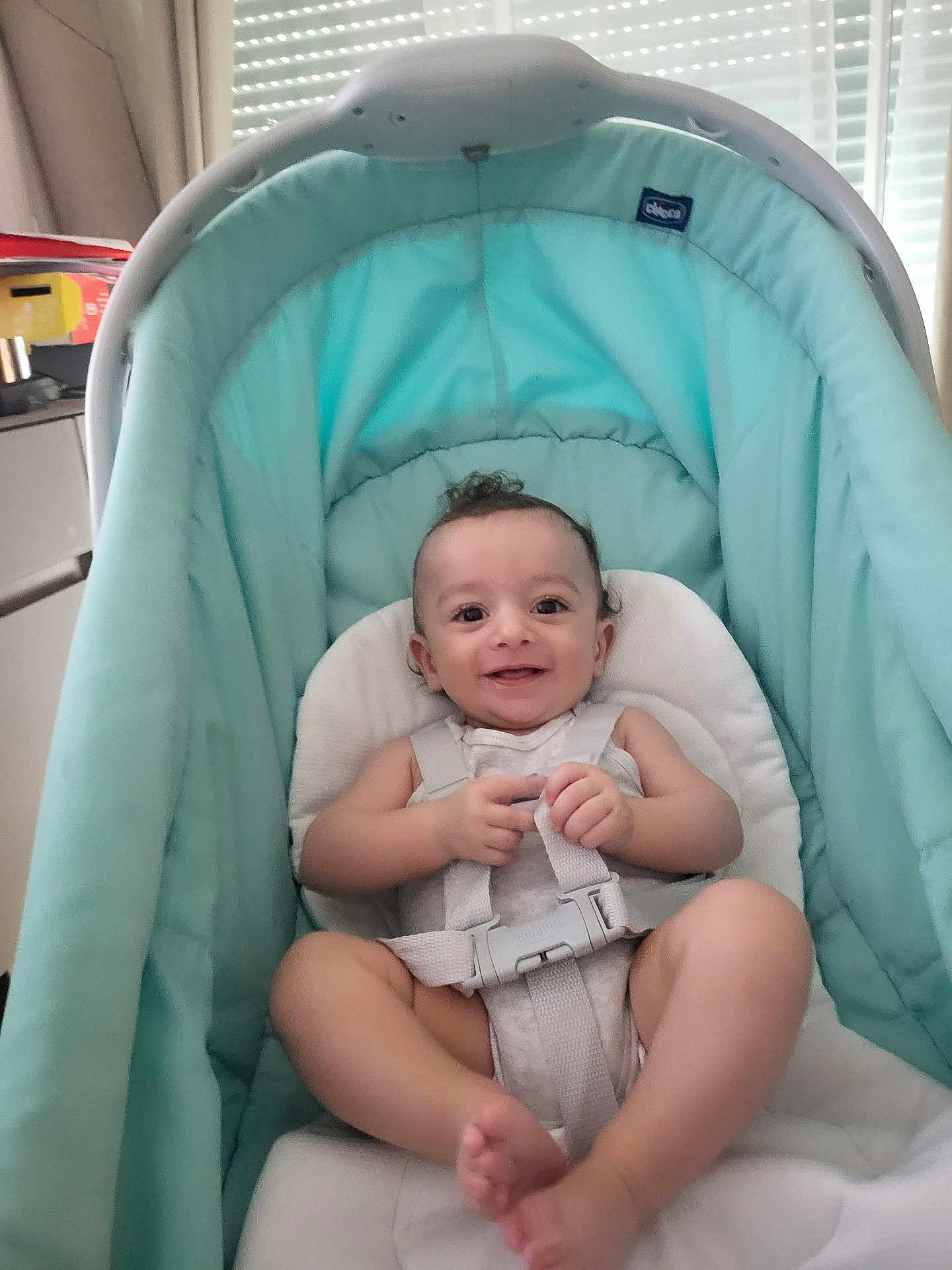 Naël a rejoint le concours — aidez-le/la à gagner de superbes lots ! baby, baby_seat, child, clothing, curly_hair, curtain, cute, face, feet, happy, harness, indoor, infant, legs, light, person, seat, skin, smiling, window