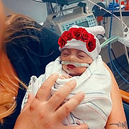 Delilah Rose Lynn joined the competition — help win amazing prizes! baby, newborn, hospital, medical_equipment, oxygen_tube, monitors, swaddled, blanket, hat, flower_crown, lipstick_filter, sparkles, adult_hand, tattoo, caregiver, tubing, neon_monitor, close_up, portrait, sleeping