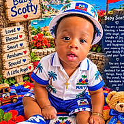 Scottie Pierre joined the competition — help win amazing prizes! baby, child, infant, portrait, sitting, smiling, hat, clothing, haiti, flag, tropical, beach, mountains, ocean, flowers, teddy_bear, toy, sneakers, outdoor, colorful