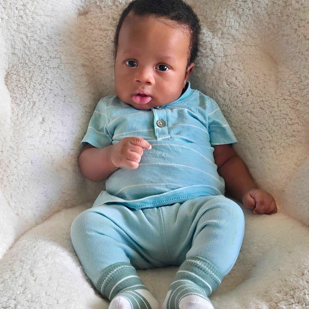 Scottie joined the competition — help win amazing prizes! baby, infant, child, blue_clothing, socks, blanket, soft_texture, cute, portrait, seated, indoors, curious_expression, cozy, comfortable, young_child, human, skin, face, hand, feet