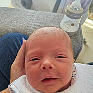 Ambre participe au concours pour gagner de l'argent avec cette photo : newborn, baby, infant, face, closeup, bib, hand, bottle, couch, fabric, person, skin, head, sleepy, smile, indoor, holding, comfort, young, rest