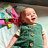 baby, child, infant, portrait, smiling, happy, lying_down, crib, nursery, green_outfit, romper, buttons, toy, colorful_toy, blanket, bedding, indoor, close_up, face, playtime