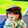 Spencer joined the competition — help win amazing prizes! baby, infant, child, sunglasses, sun_hat, pacifier, outdoor, patio, grass, vehicle, seated, portrait, clothing, onesie, green, blue, happy, funny, face, photography