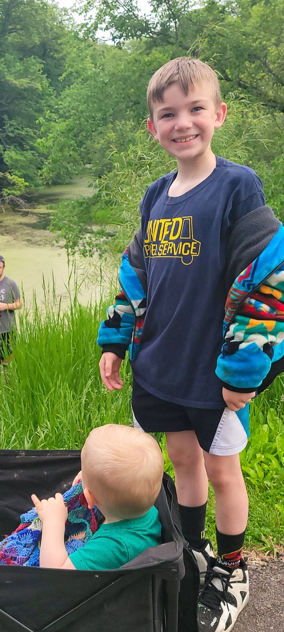 Logan is registered to the contest to win money with this photo: blue, blurred, botany, electric_blue, facial_expression, fun, grass, green, hairstyle, happy, joy, leisure, people_in_nature, person, personal_protective_equipment, plant, recreation, shorts, sleeve, smile