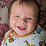 baby, smile, infant, face, happy, onesie, animal_print, giraffe, lion, zebra, child, portrait, cute, toddler, closeup, indoors, blanket, pattern, hair, skin
