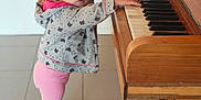 Love participe au concours pour gagner de l'argent avec cette photo : toddler, child, piano, musical_instrument, hoodie, pink_leggings, pink_sneakers, hair_tie, standing, curious, indoors, tile_floor, wooden_piano, keys, cute, portrait, small_hands, playing, young_child, casual_clothing