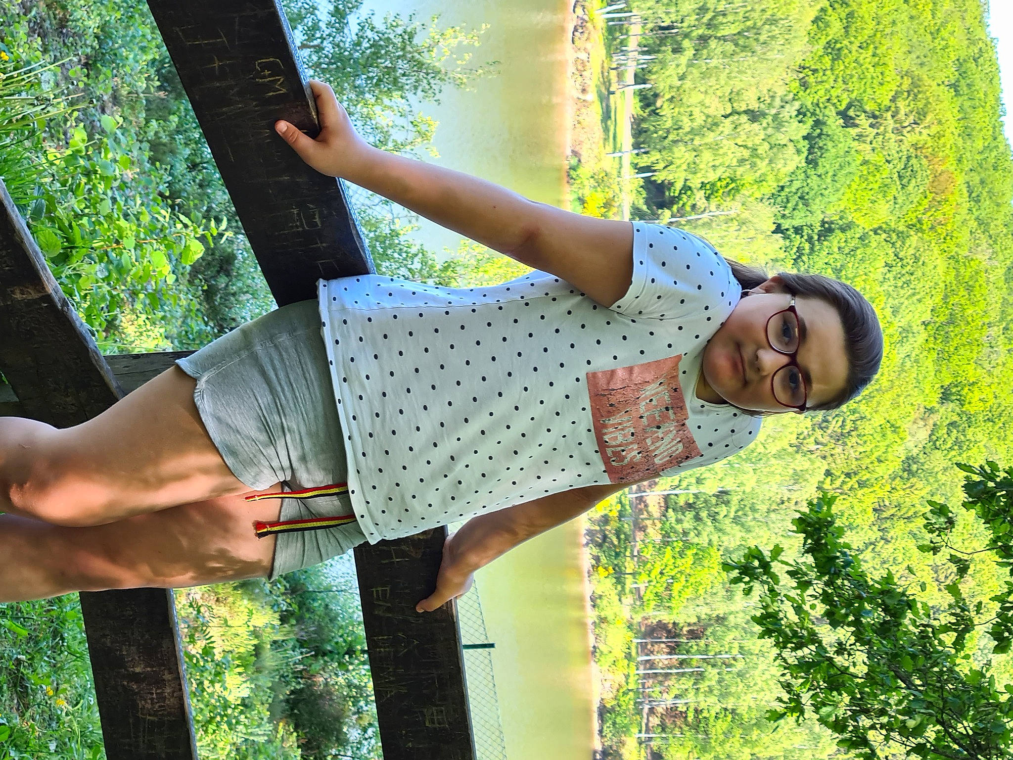 Manon participe au concours pour gagner de l'argent avec cette photo : elbow, eyewear, fun, gesture, grass, happy, human_leg, joint, leisure, pattern, people_in_nature, person, plant, sleeve, sunlight, t_shirt, tree, trunk, vegetation, waist