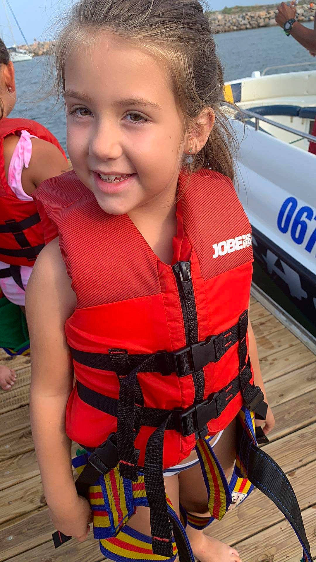 Elea participe au concours pour gagner de l'argent avec cette photo : boats_and_boating_equipment_and_supplies, child, facial_expression, fun, happy, human_leg, joy, leisure, lifejacket, orange, pattern, person, personal_protective_equipment, recreation, skin, smile, thigh, toddler, tourism, travel