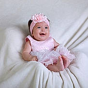 Deyna joined the competition — help win amazing prizes! baby, child, pink_dress, headband, flower, smiling, happy, infant, cute, soft_blanket, sitting, portrait, indoors, young_child, skin, feet, hands, headwear, fashion, adorable